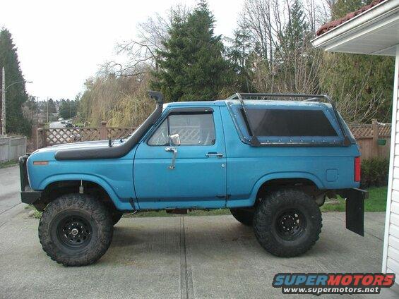 Lifted blue 1980s Ford Bronco with snorkel and roof rack.