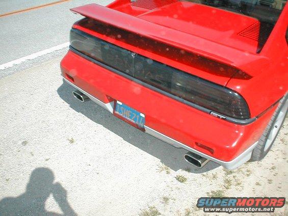 Red 1986 Pontiac Fiero with a spoiler and dual exhaust pipes. License plate reads 'ISHE211'