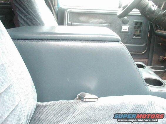 Interior of a vehicle showing a blue center console and seat with a seatbelt buckle.
