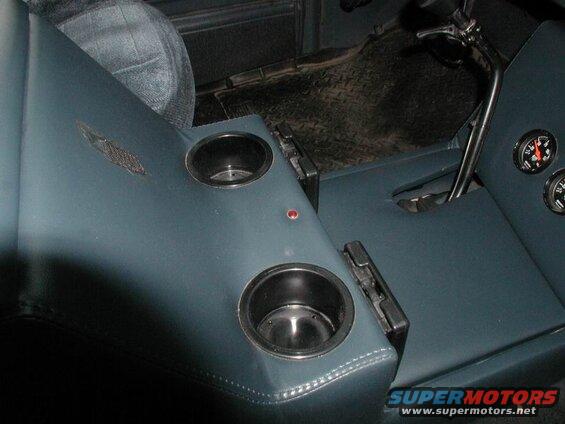 Interior view of a vehicle's center console with cup holders and gauges.