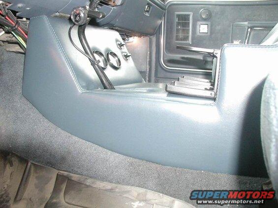 Interior of a vehicle showing a custom blue center console with gauges and gear shifter.