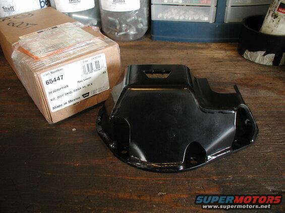 Black differential skid plate and its packaging on a wooden workbench.