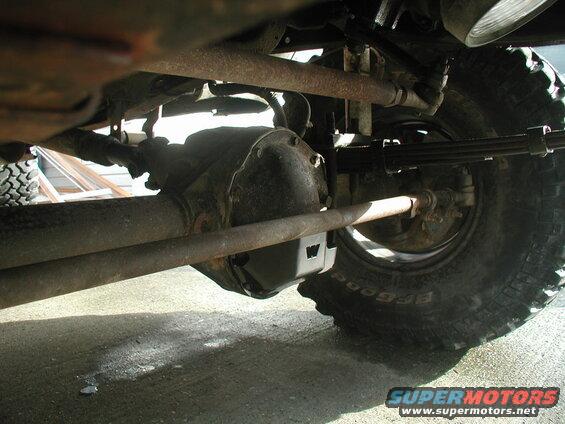 Underside of a vehicle showing front axle, steering, leaf spring, and tire.