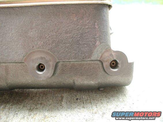 Close-up of cast metal part with two threaded ports and brass fittings.