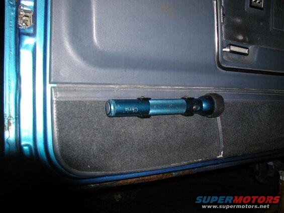 Blue flashlight mounted on the interior door panel of a vehicle.