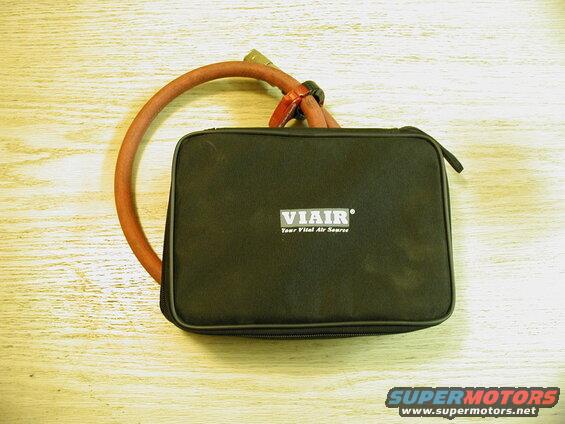 Black VIAIR air source carrying case with red air hose on a wooden table.