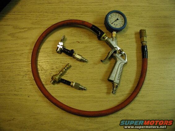 Air pressure gauge, blow gun, and tire chucks on a wooden surface.