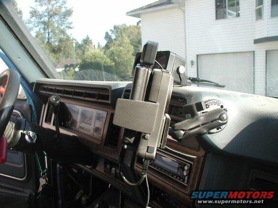 Interior view of a vehicle dashboard with a mounted communication device and steering wheel.