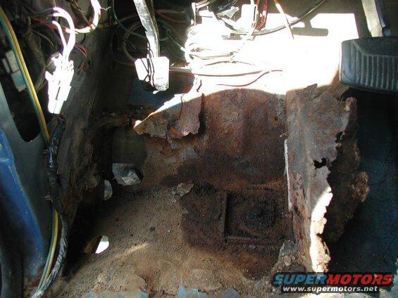 Here is what is left of the drivers side floor.I already had a patch where the dimmer switch was, but now I'll have to make a larger patch. I spent about 15 minutes scraping all the dirt and debrit out of there. You can see the two holes where dirt got in; why did Ford leave such large holes?????