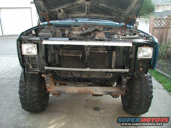 Teal Ford Bronco front view with hood open, showing engine and tires.