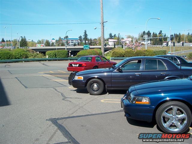 Dark blue 2001 Ford Crown Victoria side view with a red sedan and another blue car