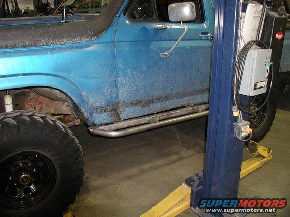 Blue Ford Bronco side view with snorkel and side steps on a car lift.