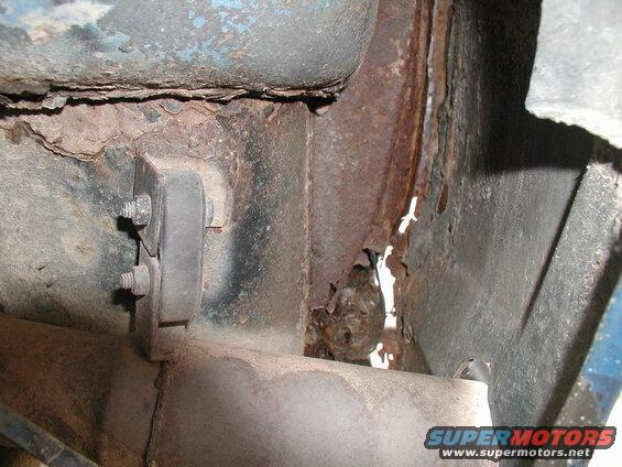 Severe rust and corrosion on vehicle undercarriage near exhaust mount.