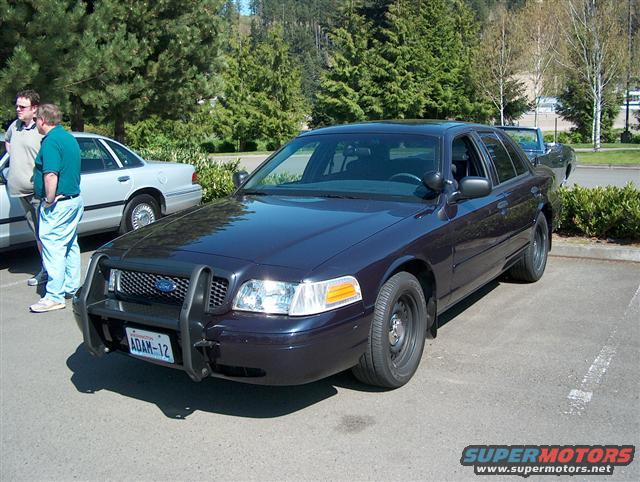 Dark blue 2001 Ford Crown Victoria police car with push bumper, parked next to a silver sedan