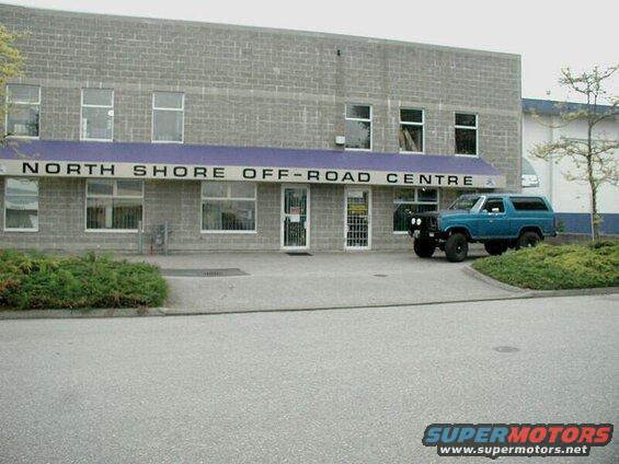 Blue 1985 Ford Bronco parked in front of North Shore Off-Road Centre building.