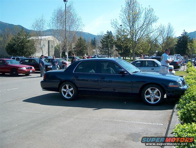 Dark blue 2001 Ford Crown Victoria parked next to a curb with other cars and people around