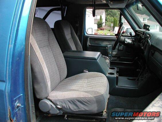 Interior of a blue Ford Bronco showing front seats, center console, dashboard, and roll cage.