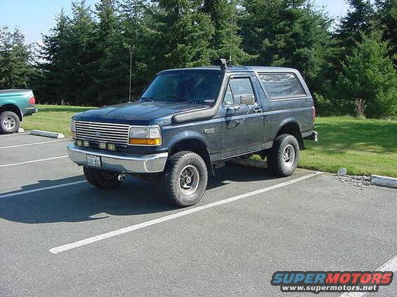 Dark blue Ford Bronco with snorkel parked in a lot.