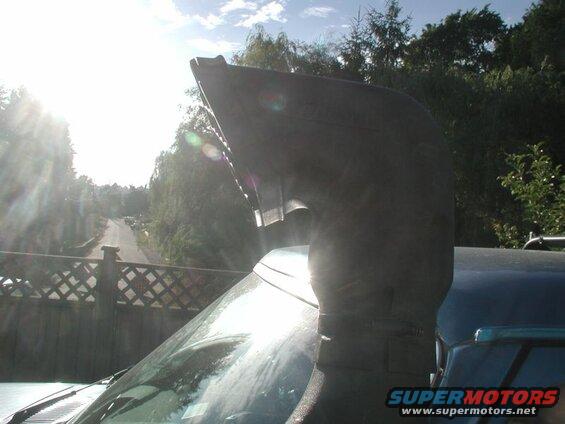 Snorkel intake on a dark blue SUV, viewed from a low angle looking up a road.
