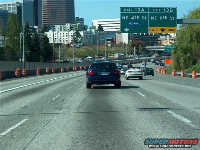 Blue sedan on highway, exit signs for NE 4th St and NE 8th St