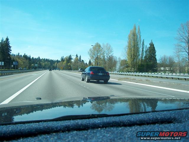 Driving on a highway with trees and other cars visible