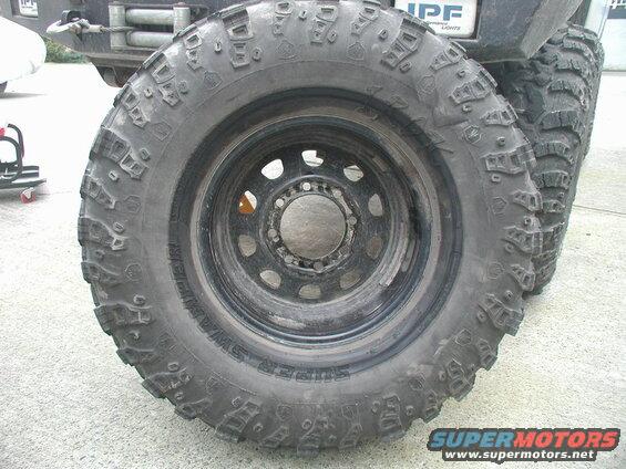 Close-up of a Super Swamper off-road tire on a black rim.