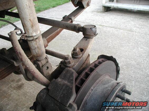 Close-up of vehicle suspension and brake components, including shock, leaf springs, and rotor.
