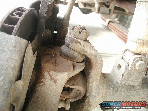 Close-up of a dirty vehicle ball joint assembly and brake rotor.