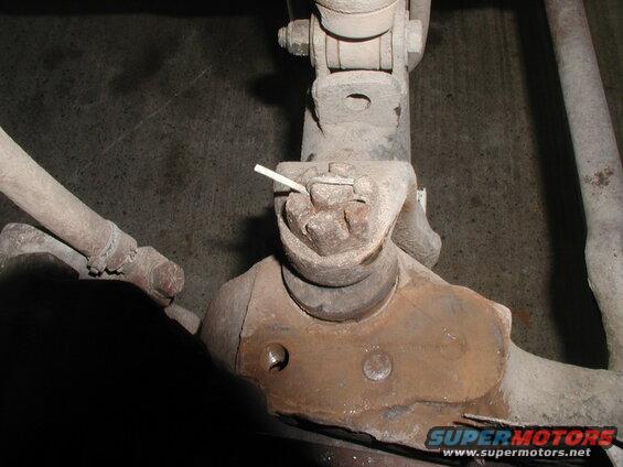 Close-up of a rusted ball joint assembly with a cotter pin.