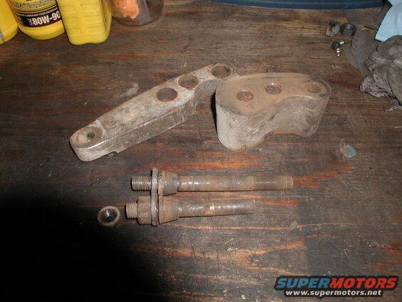 Rusty metal brackets and bolts on a wooden workbench with a bottle of oil.