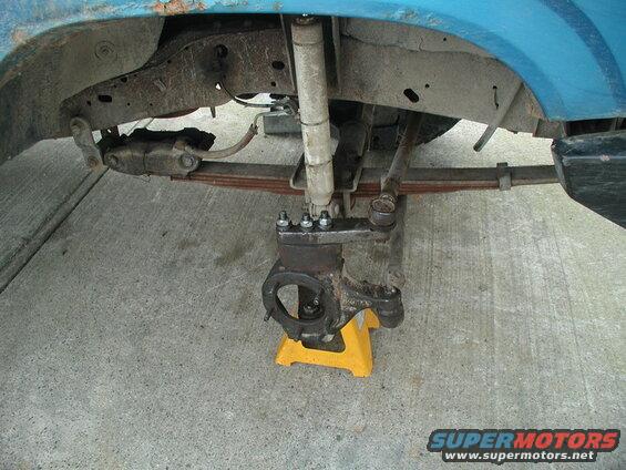 Blue Ford Bronco front suspension with wheel removed, supported by jack stand.
