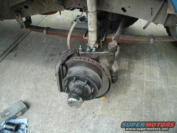 Underside of a vehicle showing suspension and brake components during repair.