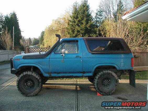 Blue 1980s Ford Bronco with snorkel and large tires, side view.