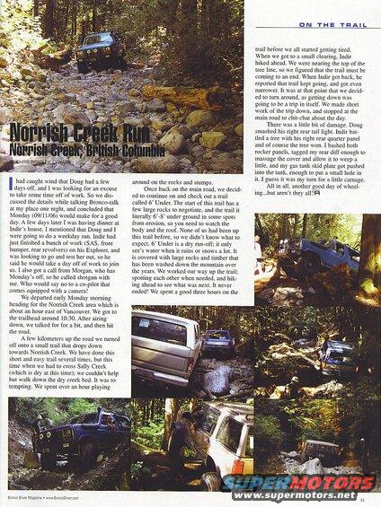 Blue 1985 Ford Bronco driving on a rocky, wooded trail.