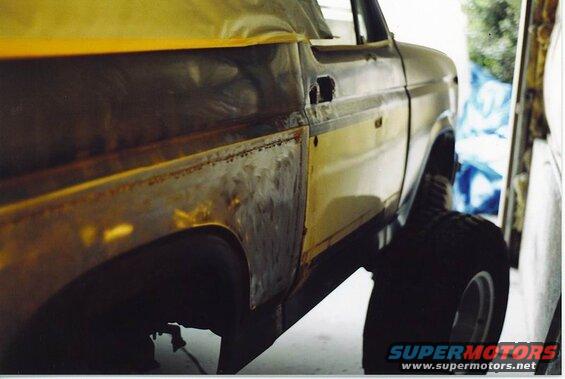 Yellow Ford Bronco side view, showing rust repair on quarter panel.