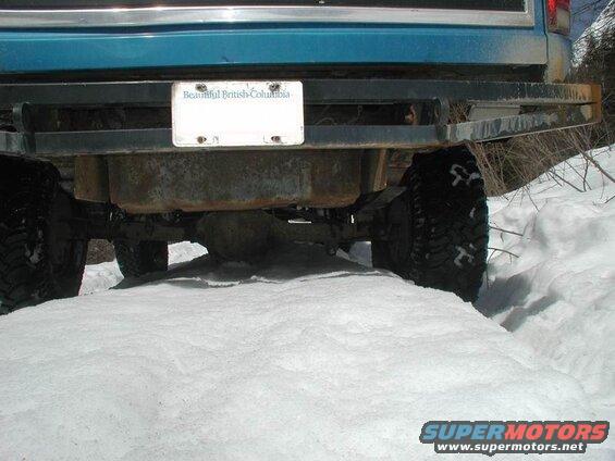 Rear view of a blue Ford Bronco in the snow, showing bumper, tires, and license plate.