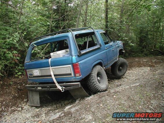 Blue Ford Bronco off-roading on a rocky trail, rear view.
