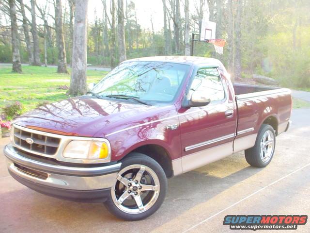 Maroon and tan 1997 Ford F-150 pickup truck with aftermarket wheels, parked outdoors