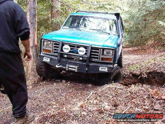 Blue Ford Bronco stuck in a ditch off-road.