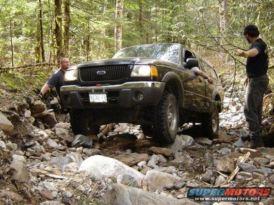 Dark Ford pickup truck on a rocky trail with two men.