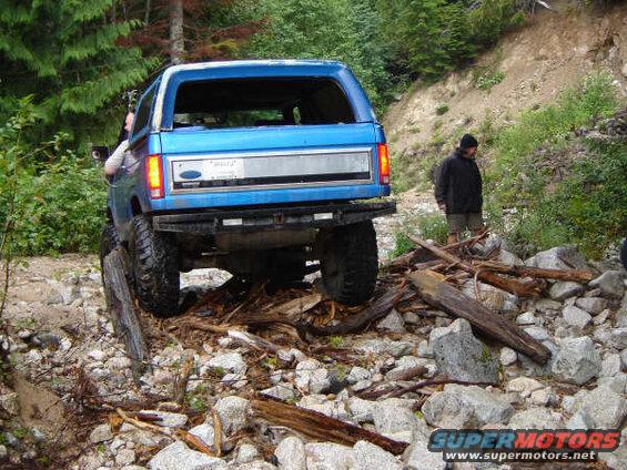 Blue Ford Bronco on a rocky trail with a person watching.