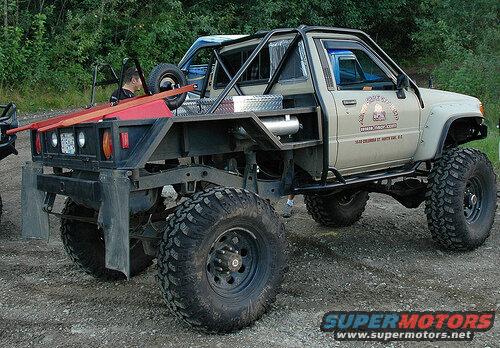 Modified lifted pickup truck with off-road tires and custom flatbed.
