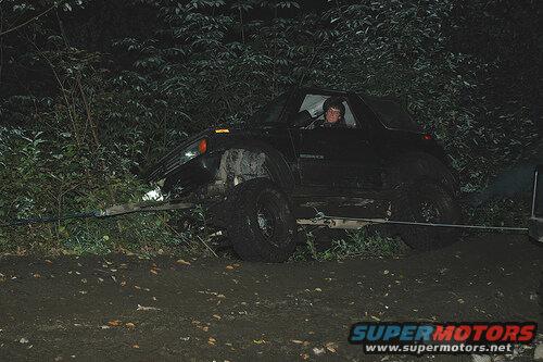 Black SUV being winched out of a ditch at night