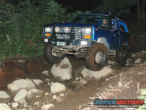 1985 Ford Bronco on a rocky trail at night.