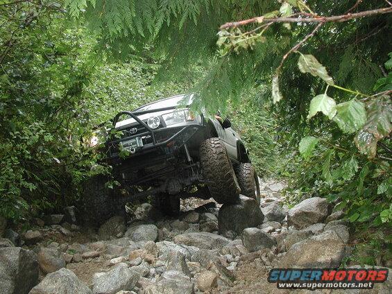 Lifted Toyota 4Runner off-roading on a rocky, wooded trail.
