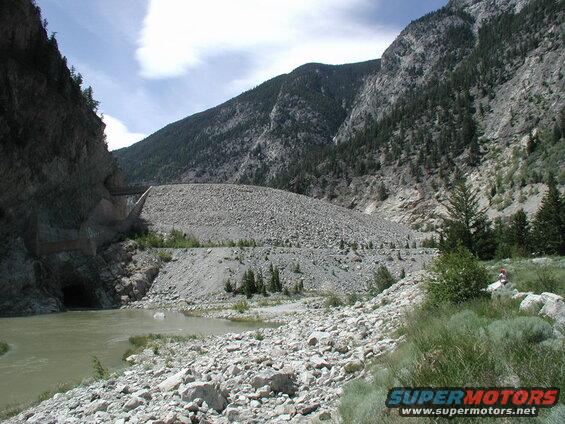 River flowing through a rocky mountain pass with a tunnel entrance.