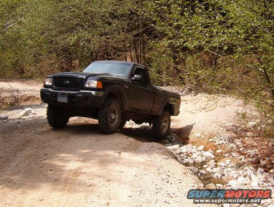 Black Ford Ranger pickup truck on a rocky off-road trail.