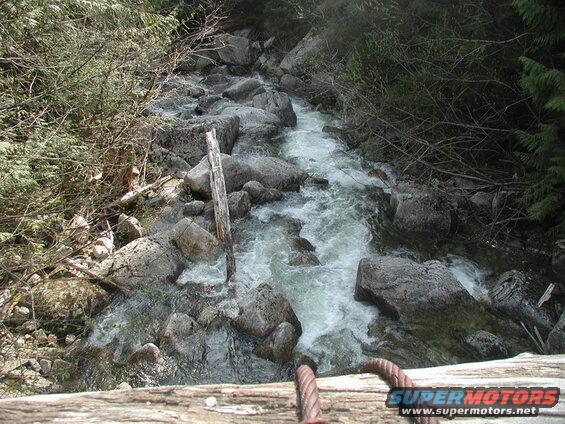A stream flowing over rocks with wooden structure and cables in the foreground.