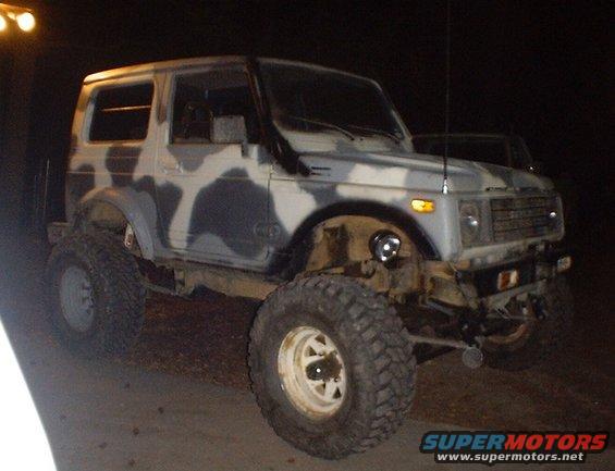 Camouflaged Suzuki Samurai with large off-road tires and aftermarket bumper