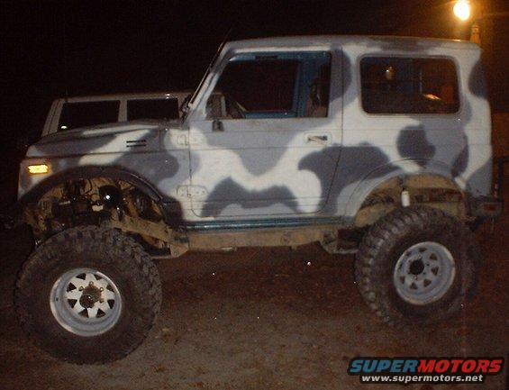 Side view of a camouflage Suzuki Samurai with large tires and lifted suspension
